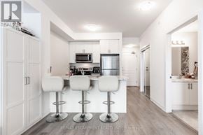 Hamilton (Waterdown) condo for rent - A modern kitchen with white bar stools and a white countertop.