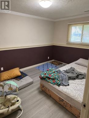 St. Catharines (Secord Woods) apartment for rent - A bedroom with a bed, a baby bouncer, and a window.