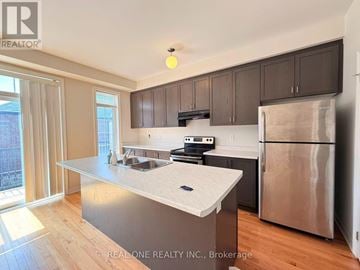 East Gwillimbury (Sharon) townhouse for rent - A kitchen with a stainless steel refrigerator and a countertop with a sink.