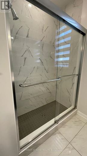 Ottawa apartment for rent - A shower with a glass door and a marble wall.
