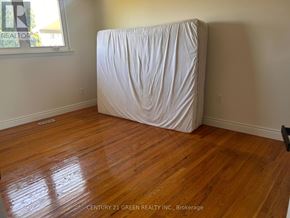 Mississauga (Malton) apartment for rent - A white sofa is covered with a white sheet in a room with wooden floors.