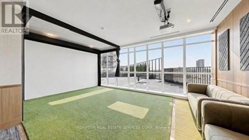 Toronto (Bayview Village) condo for rent - A spacious living room with a green carpet and a large window overlooking a cityscape.