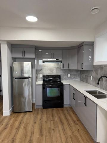 Edmonton apartment for rent - A kitchen with a black oven and a stainless steel refrigerator.