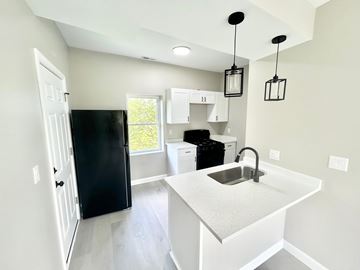 Gary apartment for rent - A kitchen with a black refrigerator and white cabinets.