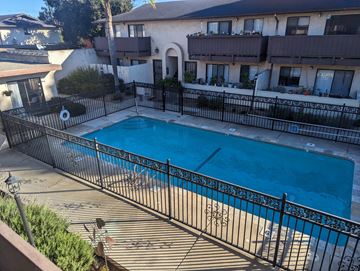 Arroyo Grande apartment for rent - A pool surrounded by a black fence with a building in the background.