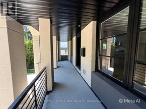 St. Catharines (Burleigh Hill) apartment for rent - A balcony with a railing and a view of trees and a building in the distance.