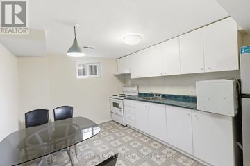 Toronto (Bayview Woods-Steeles) apartment for rent - A kitchen with white cabinets and a glass table.