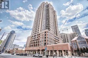 Mississauga (City Centre) condo for rent - A tall building with a lot of windows is in the middle of a city street.