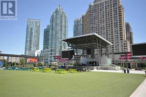 Mississauga (City Centre) condo for rent - A large grassy area with a stage and seating area in front of a city skyline.