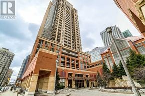 Mississauga (City Centre) condo for rent - A tall building with a glass facade stands in front of a red brick building.