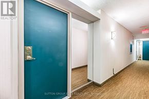 Mississauga (Cooksville) condo for rent - A hallway with a blue door and a red exit sign.
