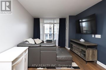 Toronto (Islington-City Centre West) condo for rent - A living room with a grey sofa and a television on the wall.