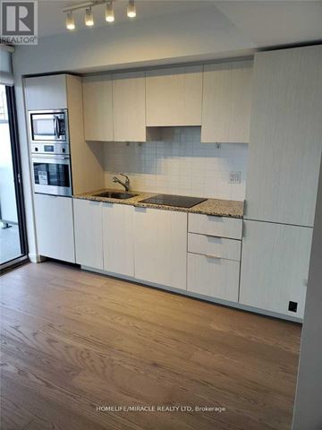 Toronto (Bay Street Corridor) condo for rent - A kitchen with white cabinets and a wooden floor.