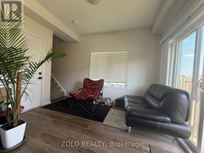 Cambridge townhouse for rent - A living room with a black leather couch, a red and black plaid chair, and a potted plant.
