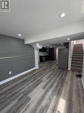 Oshawa (Eastdale) apartment for rent - A spacious room with wooden flooring and a staircase in the background.
