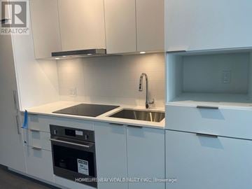 Toronto (Newtonbrook East) condo for rent - A modern kitchen with white cabinets and a stainless steel oven.