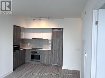 Toronto (Waterfront Communities) condo for rent - A modern kitchen with wooden cabinets and a stainless steel oven.