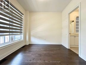Bradford West Gwillimbury (Bond Head) apartment for rent - A room with wooden floors and white walls, with a doorway leading to another room.