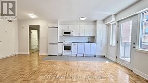 Toronto (Yonge-St. Clair) condo for rent - A well-lit, empty apartment with wooden flooring and white walls.