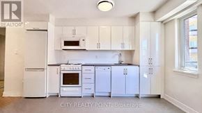 Toronto (Yonge-St. Clair) condo for rent - A white kitchen with a refrigerator, oven, microwave, and cabinets.
