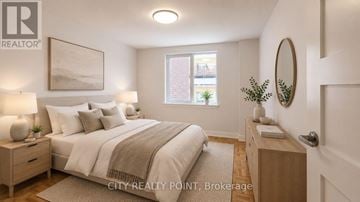 Toronto (Yonge-St. Clair) condo for rent - A well-lit bedroom with a large bed and a nightstand with a lamp.