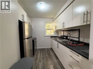 Waterloo townhouse for rent - A kitchen with white cabinets and a black countertop.