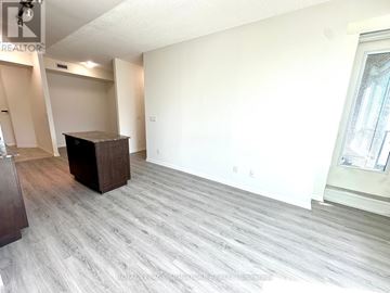 Toronto (Waterfront Communities) condo for rent - A spacious living room with a grey carpet and a wooden cabinet.