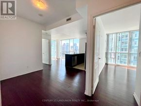 Mississauga (City Centre) condo for rent - A spacious room with wooden floors and a large window overlooking the city.