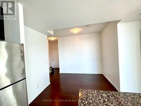 Mississauga (City Centre) condo for rent - A spacious room with a refrigerator on the left side and a rug on the floor.