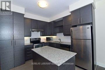 Markham (Commerce Valley) condo for rent - A kitchen with dark wood cabinets and stainless steel appliances.