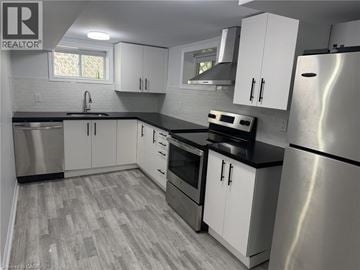 Milton townhouse for rent - A kitchen with white cabinets and a stainless steel refrigerator.