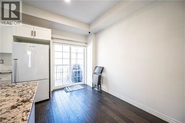 Kitchener townhouse for rent - A kitchen with a refrigerator and a chair in the living room.