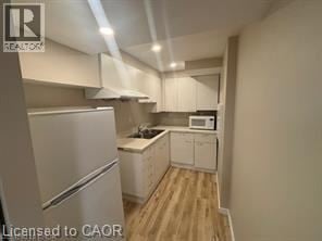 Kitchener apartment for rent - A kitchen with a refrigerator, microwave, and cabinets.