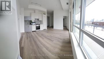 Toronto (Kensington-Chinatown) condo for rent - A spacious kitchen with white cabinets and a large window overlooking the city.
