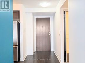 Toronto (Etobicoke West Mall) condo for rent - A hallway with a door and a refrigerator on the left.