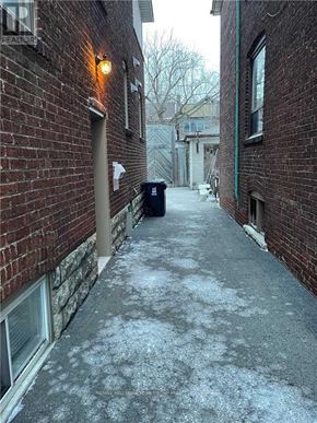 Toronto (Corso Italia-Davenport) apartment for rent - A narrow alley with a brick wall and a metal trash can.
