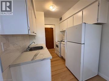 Hamilton apartment for rent - A kitchen with white cabinets and a white fridge.