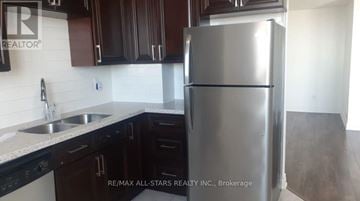 Toronto (Malvern) condo for rent - A kitchen with a stainless steel refrigerator and black cabinets.