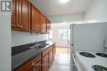 Burlington (Brant) condo for rent - A kitchen with brown cabinets and a white stove top oven.