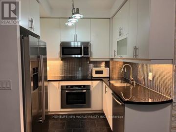 Toronto (Bay Street Corridor) condo for rent - A kitchen with white cabinets and black countertops.
