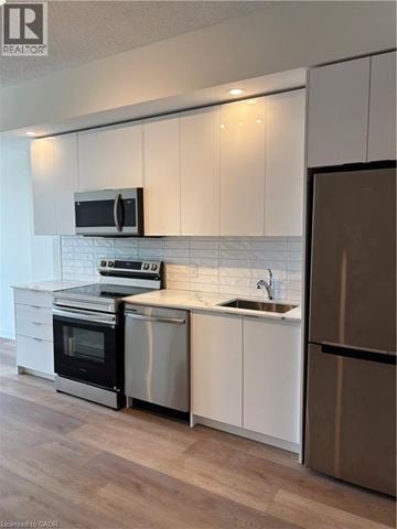 Brantford condo for rent - A modern kitchen with white cabinets and stainless steel appliances.
