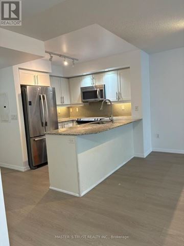 Toronto (Niagara) condo for rent - A kitchen with a refrigerator, microwave, and stove top oven.