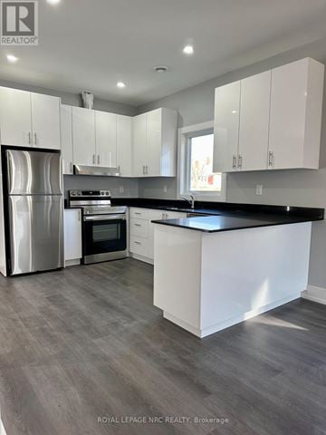 Welland (Welland Downtown) multi-family for rent - A modern kitchen with white cabinets and a stainless steel refrigerator.
