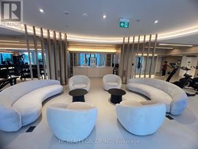 Mississauga (Mississauga Valleys) condo for rent - A modern room with white furniture and a green exit sign.