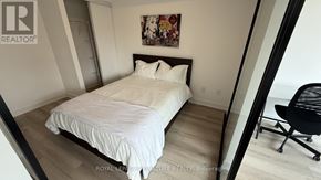 Toronto (Trinity-Bellwoods) condo for rent - A bedroom with a white bed and a black chair.