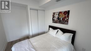 Toronto (Trinity-Bellwoods) condo for rent - A bedroom with a bed, a painting on the wall, and a sliding door.