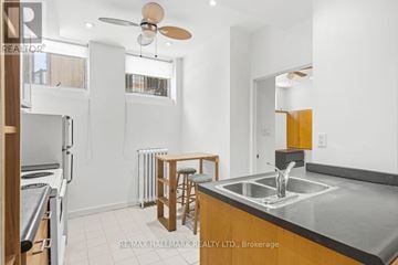 Toronto (Palmerston-Little Italy) multi-family for rent - A kitchen with a stove top oven, a bar stool, and a fan.