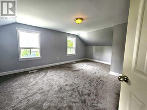 Wellington North (Mount Forest) multi-family for rent - A room with grey carpeting and two windows.