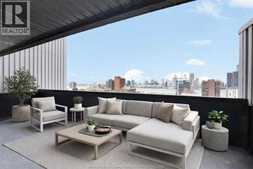 Windsor condo for rent - A living room with a couch, chair, and coffee table with a city view in the background.
