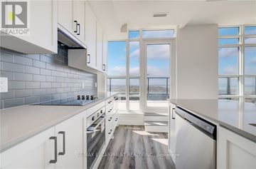 Hamilton (Lakeshore) condo for rent - A modern kitchen with white cabinets and a view of the water outside the window.